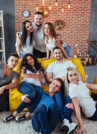 Group portrait of multi-ethnic boys and girls with colorful fashionable clothes holding friend and posing on a brick wall, Urban style people having fun, Concepts about youth and togetherness lifestyle.
